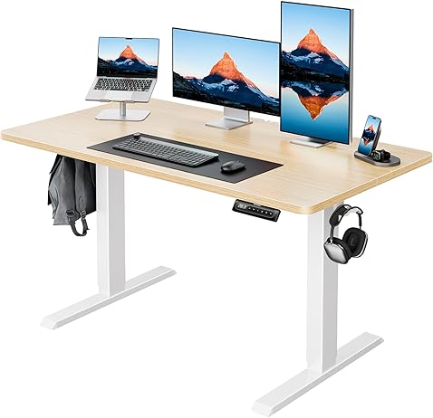 HUANUO electric standing desk with three monitors, laptop, and headset holder.