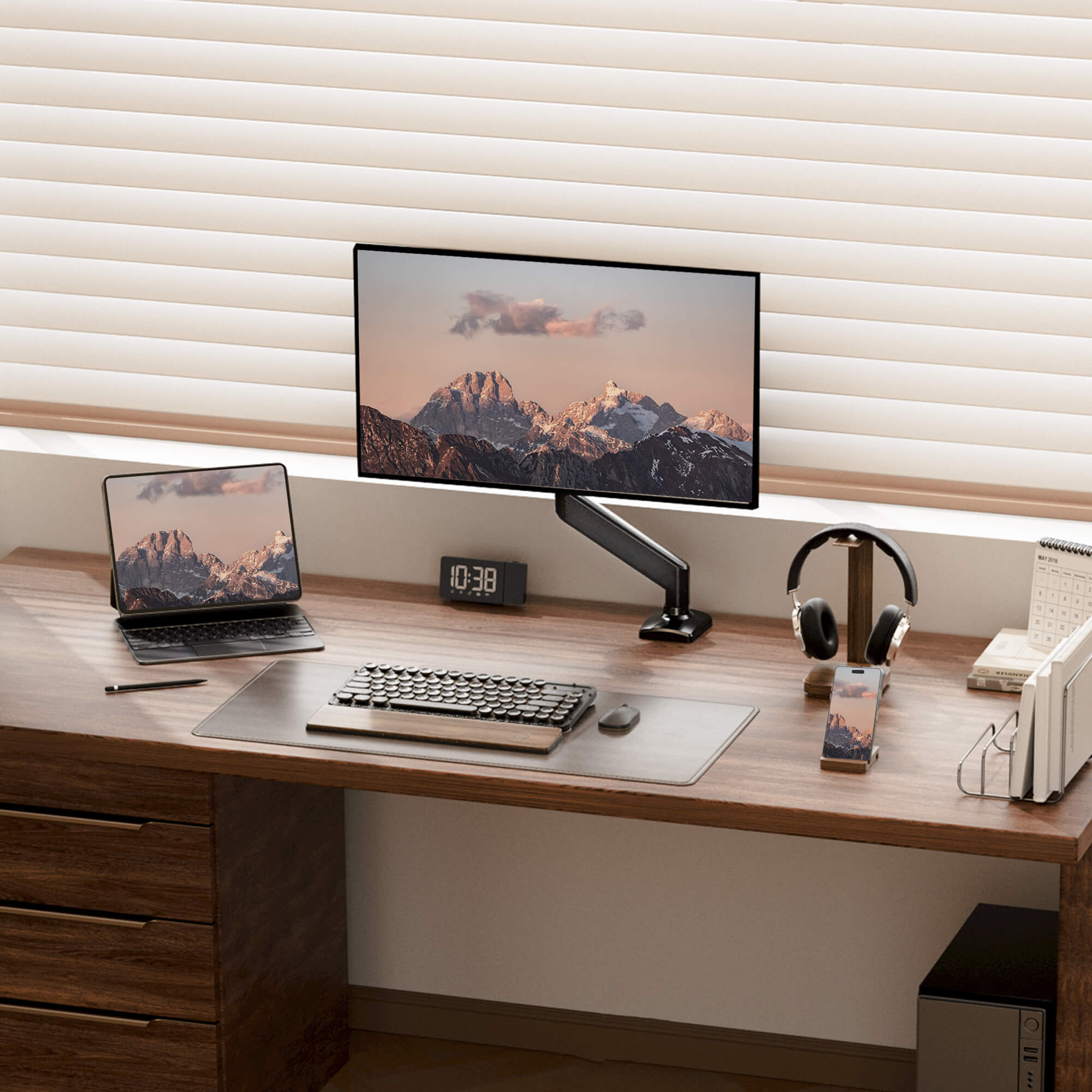 Ergonomic workspace with single monitor arm and laptop setup on a wooden desk.