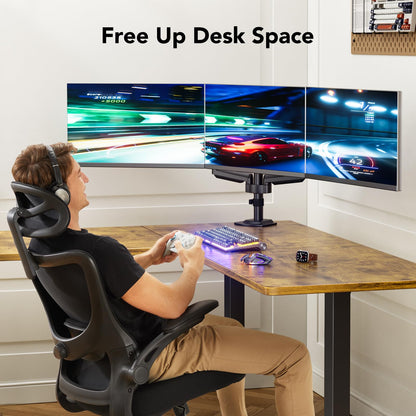 Man gaming with triple monitor setup, highlighting ergonomic desk organization.