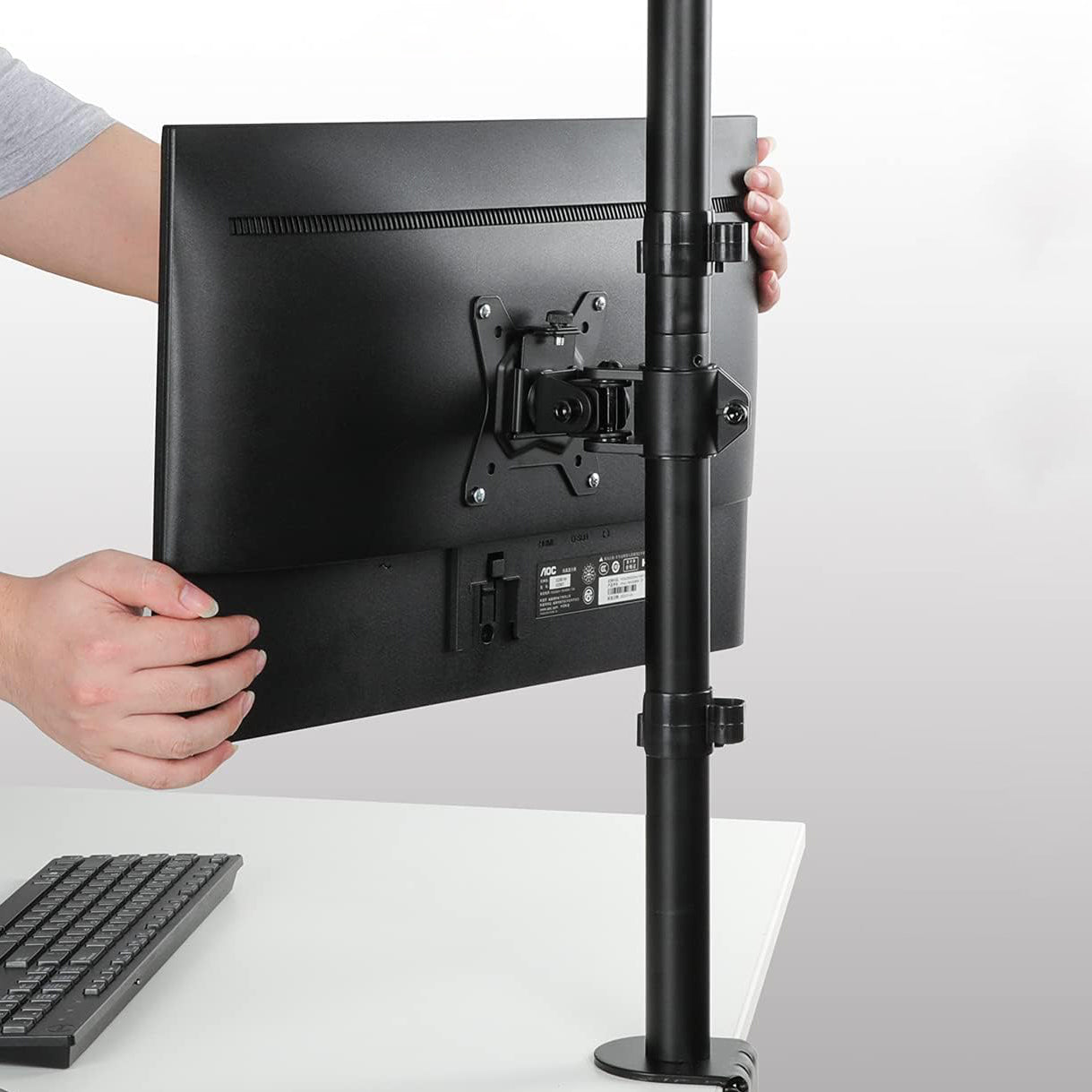 Adjusting vertical dual monitor mount for ergonomic workspace setup.